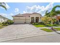 Charming one-story home with three-car garage, paved brick driveway, red tile roof, and lush landscaping at 5428 Royal Poinciana Way, North Port, FL 34291