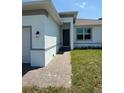 Charming home featuring a covered entryway and a well-lit, brick walkway to front door at 7474 Manville Ter, Port Charlotte, FL 33981
