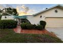 Charming single-story home with a unique architectural design, tidy landscaping, and brick walkway leading to the gate at 1305 Alton Rd, Port Charlotte, FL 33952