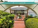 Front gated courtyard with red brick, lush landscaping, and unique architectural details at 1305 Alton Rd, Port Charlotte, FL 33952