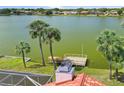 Home offers a backyard view of the lake with a small dock and mature palm trees at 149 Albert Ln, Port Charlotte, FL 33954