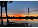 Beautiful sunset view of the water, a dock with a kayak, and a palm tree silhouetted in the dusk at 149 Albert Ln, Port Charlotte, FL 33954