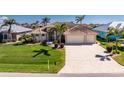 Stunning home featuring an oversized driveway, manicured lawn, and tropical landscaping in a desirable neighborhood at 15762 Aqua Cir, Port Charlotte, FL 33981