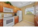 Kitchen with white appliances, light wood cabinetry, tile flooring and window with blinds at 175 Kings Hwy # 226, Punta Gorda, FL 33983