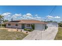 Single-story home featuring a lush lawn and a paved driveway leading to an attached garage at 18106 Petoskey Cir, Port Charlotte, FL 33948