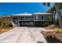 Lovely coastal home on stilts features a metal roof, lush landscaping, and a spacious driveway at 24139 Jolly Roger Blvd, Punta Gorda, FL 33955