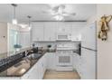 Well-lit kitchen featuring white appliances, cabinets, black granite countertops, and modern pendant lighting at 25100 Sandhill Blvd # R202, Punta Gorda, FL 33983