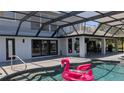 Inviting backyard pool featuring an inflatable flamingo under a screened-in lanai with outdoor kitchen at 384 Viedma St, Punta Gorda, FL 33983