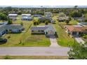 Aerial view of a residential home with green lawn, mature trees, and a paved driveway in a quiet neighborhood at 558 Azalea Drive, Port Charlotte, FL 33952