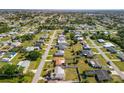Expansive aerial neighborhood view with single-Gathering homes, mature trees, and clear blue skies at 558 Azalea Drive, Port Charlotte, FL 33952
