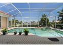 Enclosed in-ground pool, with spa, surrounded by brick pavers and tropical landscaping at 584 Toulouse Dr, Punta Gorda, FL 33950