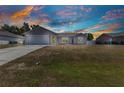 Single-story home with a neutral color scheme, attached garage, and a spacious well-maintained lawn under a dramatic sky at 6344 Hera St, Englewood, FL 34224