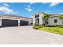 Beautiful single-Gathering home featuring a three-car garage and a paved driveway under a blue sky with clouds at 8968 Artisan Way, Sarasota, FL 34240