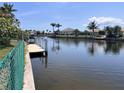 Waterfront view featuring a private dock, lush landscaping, and beautiful homes along the canal at 931 Juno Dr, Punta Gorda, FL 33950