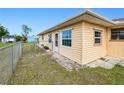 Exterior corner view showing large side yard, windows, door, and chain link fence at 167 N Cambridge Nw Dr, Port Charlotte, FL 33952