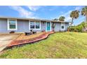 Beautifully landscaped front yard features a brick walkway leading to a charming home entrance with a vibrant blue door at 2236 Arnet St, Port Charlotte, FL 33948