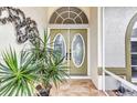 Close up of a front door with glass inserts flanked by tropical foliage at 23104 Turnbull Ave, Port Charlotte, FL 33954
