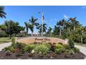Entrance sign for Emerald Pointe with lush landscaping and palm trees under a clear sky at 25188 Marion Ave # F307, Punta Gorda, FL 33950