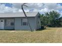 View of the side of the home, showing the yard and a leaning palm tree at 6728 Thorman Rd, Port Charlotte, FL 33981