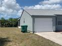 Side view of home featuring a garage, well-maintained exterior, and green trash receptacles at 6728 Thorman Rd, Port Charlotte, FL 33981