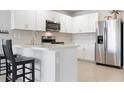 Modern kitchen with stainless steel appliances, white cabinetry, and a breakfast bar with seating at 7209 W Lenox Cir, Punta Gorda, FL 33950