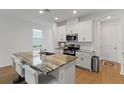 Modern kitchen featuring an island with granite countertops, stainless steel appliances, and white cabinets at 15975 Mulrion Blvd, Punta Gorda, FL 33982