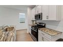 Bright kitchen featuring an island with granite countertops, stainless steel appliances, and white cabinets at 15975 Mulrion Blvd, Punta Gorda, FL 33982