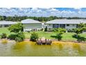 A view of the lake with a wooden dock and chairs behind a condo building at 25225 Rampart Blvd # 1607, Punta Gorda, FL 33983