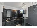 Bathroom featuring black tile, a bathtub, a shower with glass doors, and a window with natural light at 2776 Tusket Ave, North Port, FL 34286