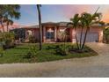 Inviting front exterior with tropical landscaping, lush green lawn, and a brick driveway, exudes curb appeal at 2779 N Beach Rd # A, Englewood, FL 34223