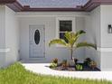 A well-maintained entrance with a decorative front door and manicured landscaping around a young palm tree at 4343 Killdeer Ter, North Port, FL 34288
