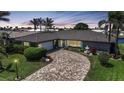 Charming home at dusk with well-manicured front yard, palm trees, fountain, and circular paver driveway at 505 Via Cintia, Punta Gorda, FL 33950