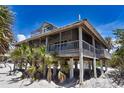 Coastal home on stilts boasting a metal roof, weathered wood, and screened wraparound porch at 8754 King St, Placida, FL 33946