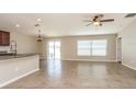 Open-concept living room featuring tile floors, ceiling fan, and sliding glass doors to the backyard at 10204 Carloway Hills Dr, Wimauma, FL 33598