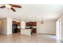 Bright, open-concept space with tile floors, ceiling fan, and a kitchen island with seating at 10204 Carloway Hills Dr, Wimauma, FL 33598