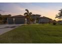 This elegant, well-manicured lawn and a lovely two-story home with a three-car garage at sunset at 13443 Boabadilla Ln, Port Charlotte, FL 33981