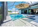 Gorgeous screened-in pool area for outdoor relaxation with an umbrella and patio seating at 13443 Boabadilla Ln, Port Charlotte, FL 33981
