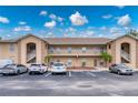 Beige condo building featuring covered stairwells, balconies, a parking lot, and tropical landscaping at 175 Kings Hwy # B2 1522, Punta Gorda, FL 33983