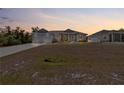 A single-story home with a two-car garage, a screened-in porch, and a vast front lawn at dusk at 2229 Wakefield St, Port Charlotte, FL 33948