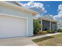 Home's exterior featuring a two-car garage, covered porch, and vibrant landscaping at 2229 Wakefield St, Port Charlotte, FL 33948