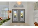 Bright foyer features gray double doors, a decorative chandelier, tile flooring, and views of the landscaped front yard at 229 Sportsman Rd, Rotonda West, FL 33947