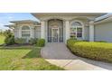Inviting front entrance with arched windows, columns, security gate, and a stone walkway leading to the front door at 229 Sportsman Rd, Rotonda West, FL 33947