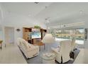 Spacious living room with tile flooring, comfortable seating, a ceiling fan, and sliding glass doors leading to the pool area at 229 Sportsman Rd, Rotonda West, FL 33947