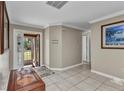 Welcoming foyer with neutral tile flooring, crown molding, and natural light through glass front door at 4178 Rose Arbor Cir, Port Charlotte, FL 33948