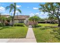 Charming home featuring a well-manicured lawn and lush tropical landscaping, including mature palm trees and healthy green shrubs at 5390 Brassy Loop, North Port, FL 34287