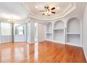 Spacious living room with hardwood floors, tray ceiling, a ceiling fan, and built-in shelving at 8315 Raoul Ave, North Port, FL 34291