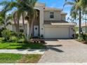 Beautiful two-story home with a well-manicured lawn, brick driveway, and a two-car garage at 11663 Anhinga Ave, Venice, FL 34292