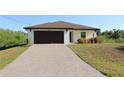 Charming one-story house with a brick-paved driveway, dark brown garage door and neatly trimmed landscaping at 17374 Gadsen Ave, Port Charlotte, FL 33948