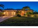 Charming house with lush landscaping, well manicured lawn, tile roof, and a two car garage shown at twilight at 211 Lido Dr, Punta Gorda, FL 33950