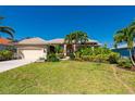 Charming single-story home with lush landscaping, mature palm trees, and a vibrant red front door at 211 Lido Dr, Punta Gorda, FL 33950